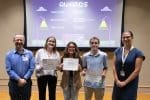 Wake Forest project management students holding their awards in front of a projection screen displaying the award winners.